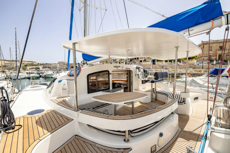 Chiquita catamaran's cockpit and outdoor dining table, moored in a Malta marina