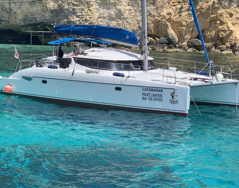 Chiquita catamaran anchored near a rocky Malta coastline
