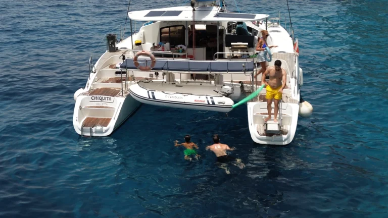 Guests swimming off the back of Chiquita catamaran, name plate visible