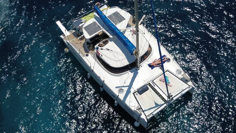 Aerial view of Chiquita catamaran anchored with a guest relaxing on the bow
