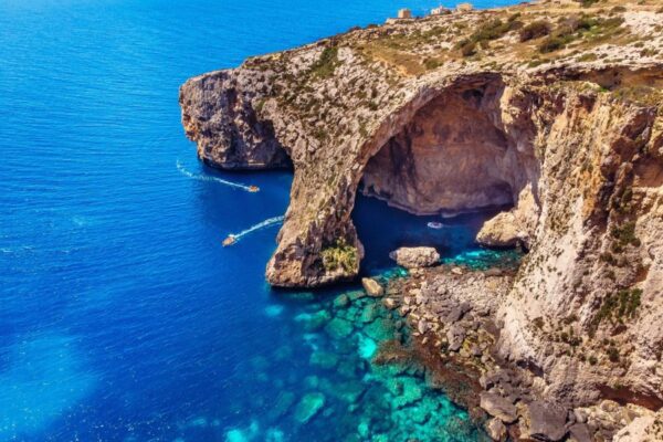 Blue Grotto sea arch on Malta's south coast with small boats in clear blue water