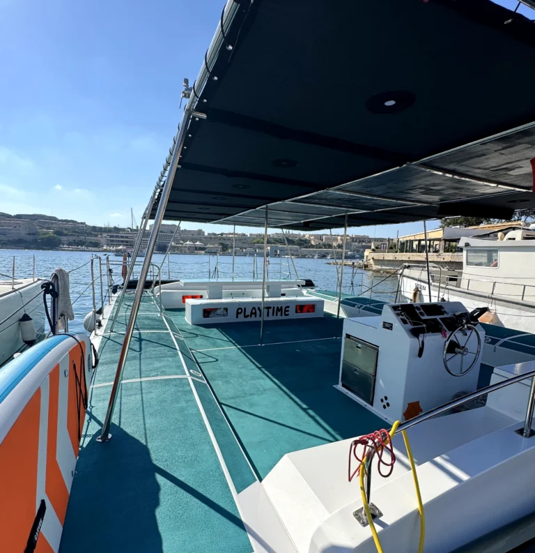 Offenes Deck und Steuerstand des im Yachthafen vor Anker liegenden Playtime-Katamarans.