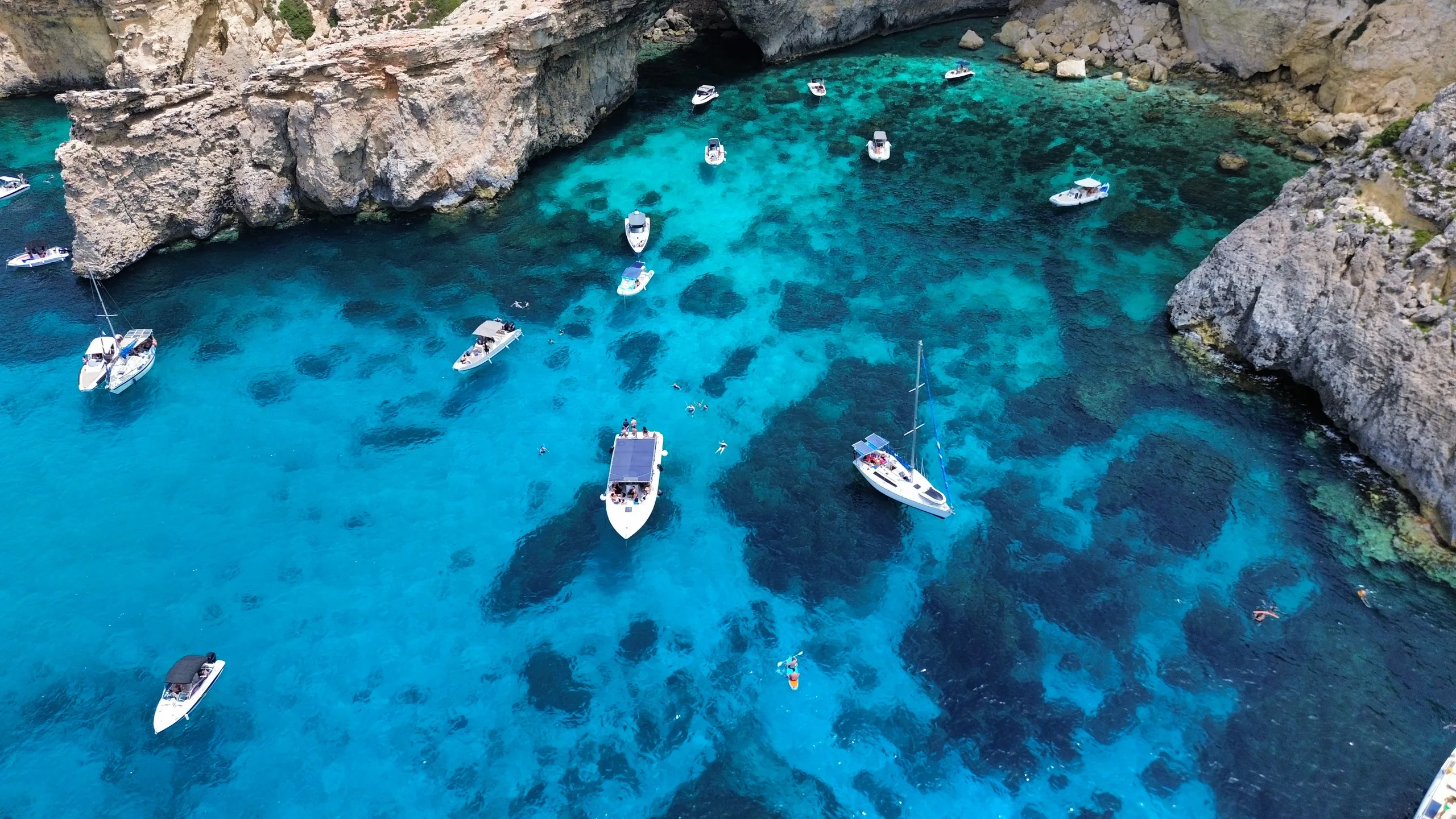 Aerial view of the Crystal Lagoon in Comino, Malta, with private charter boats anchored in turquoise water
