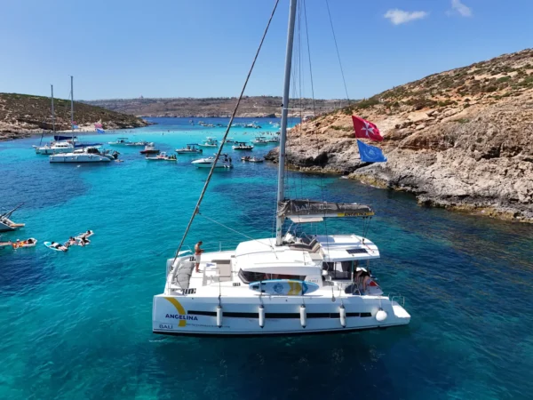 Angelina Mia catamaran at the Blue Lagoon, Comino, with guests swimming nearby