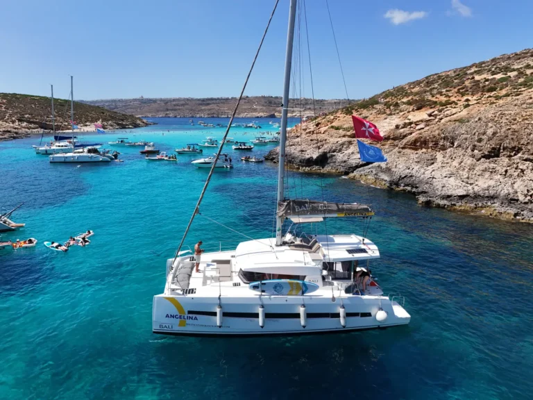 Angelina Mia catamaran at the Blue Lagoon, Comino, with guests swimming nearby