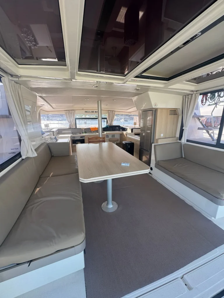 Shaded cockpit lounge with dining table and cushioned seating on the Angelina Mia catamaran