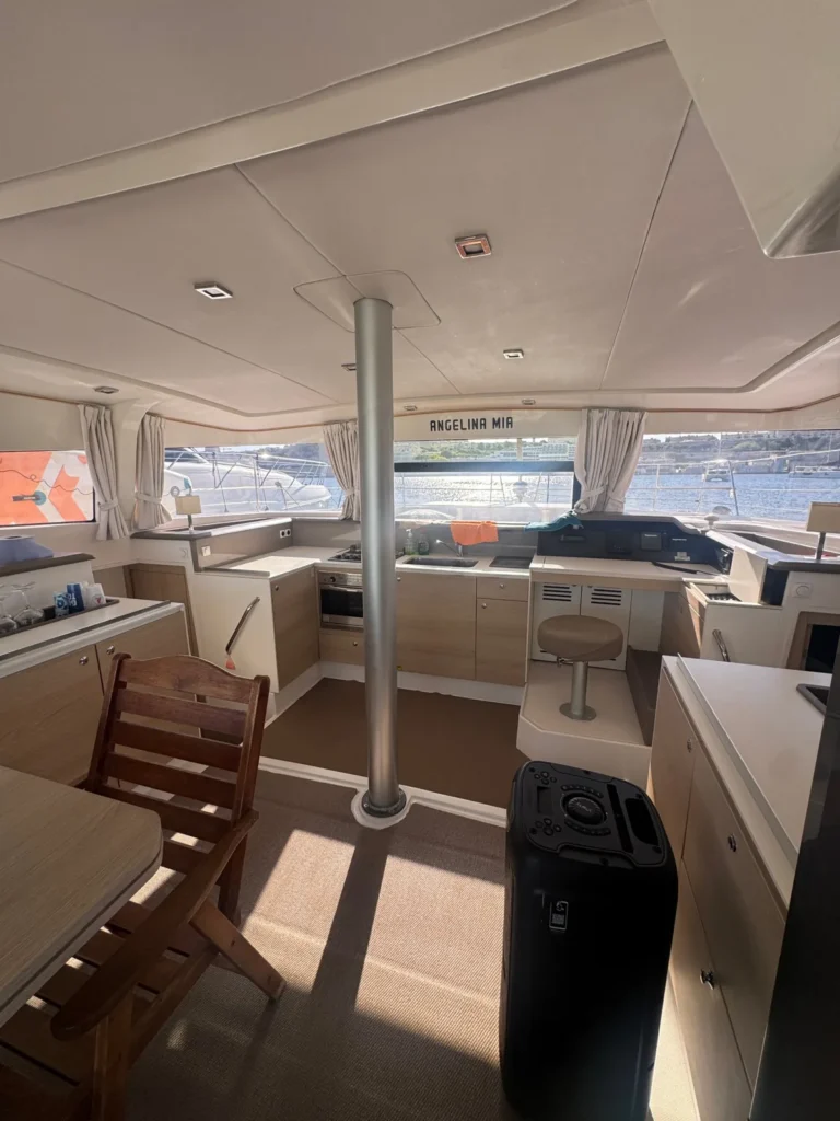 Inside the Angelina Mia catamaran: galley, helm station and harbour views through the saloon windows